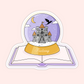 A magical vinyl sticker featuring a fantasy castle snow globe sitting on an open book. Perfect for fantasy readers and whimsical bookish vibes.