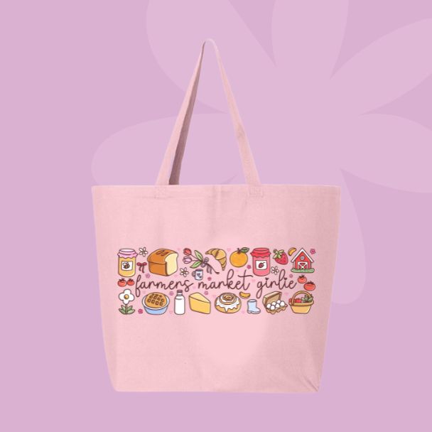 Large pink canvas tote bag featuring the words farmers market girlie surrounded by jam, bread, mushrooms, produce, cheese, flowers, and market-inspired doodles.