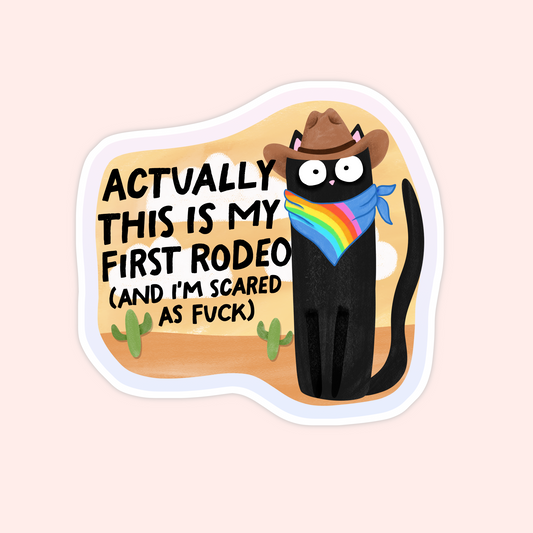 Black cat in a cowboy hat and rainbow bandana with the phrase "Actually this is my first rodeo (and I’m scared as f***)."