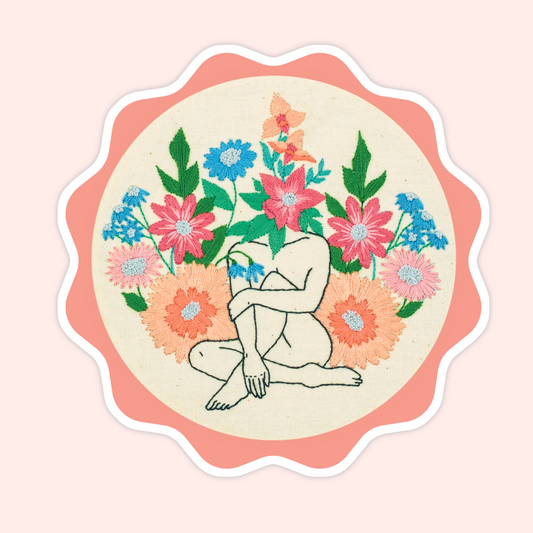 Sticker of original embroidery art featuring a seated body outline surrounded by colourful embroidered flowers.