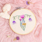 Hand embroidered floral uterus embroidery hoop wall art in a 6 inch wooden hoop styled on pink background with crystals and dried flowers