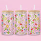 Glass cup with pink background covered in colorful fruits (watermelon, strawberries, blueberries, cherries) and spring flowers (daisies, tulips, daffodils).