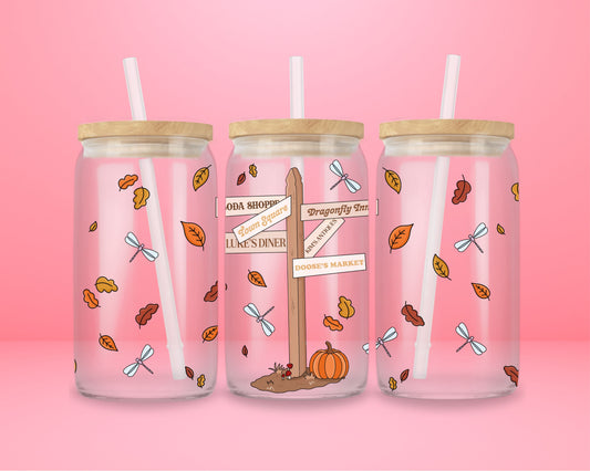 glass tumbler with wooden lid and straw featuring Stars Hollow signpost with “Luke’s Diner,” “Doose’s Market,” “Town Square,” and fall leaves.