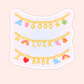 Charm bracelet style sticker with colorful charms spelling “Good Luck Babe,” pop music inspired aesthetic sticker.