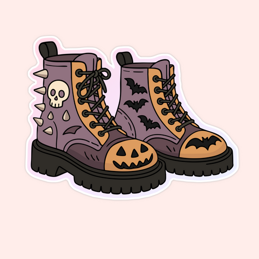 Sticker of purple combat boots decorated with bats, skulls, spikes, and jack-o’-lantern faces.