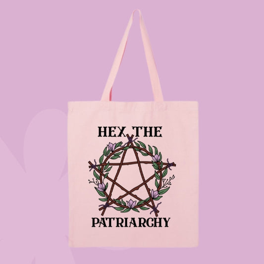 Pink tote bag with a pentagram made of branches and pink flowers, with bold text that says “Hex the Patriarchy.”