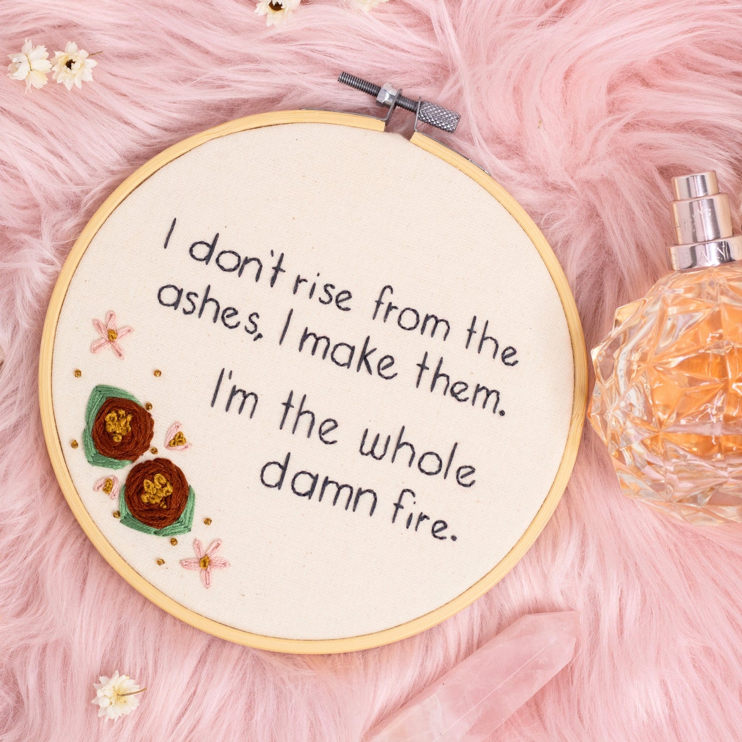 Hand embroidered feminist quote hoop reading I’m the whole damn fire styled on pink faux fur with crystals and perfume bottle