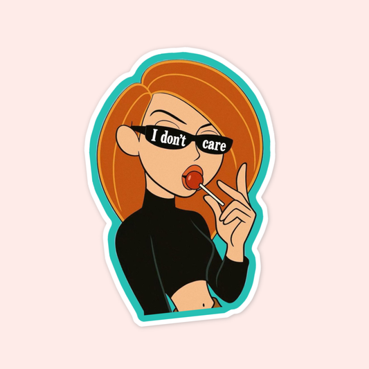 Kim Possible-inspired sticker featuring a red-haired cartoon girl wearing black sunglasses that say “I don’t care” while holding a lollipop.