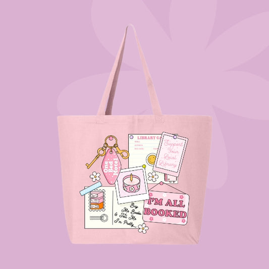 Pink tote bag with a pink collage design featuring a library card, candle, and text that says “I’m All Booked.”