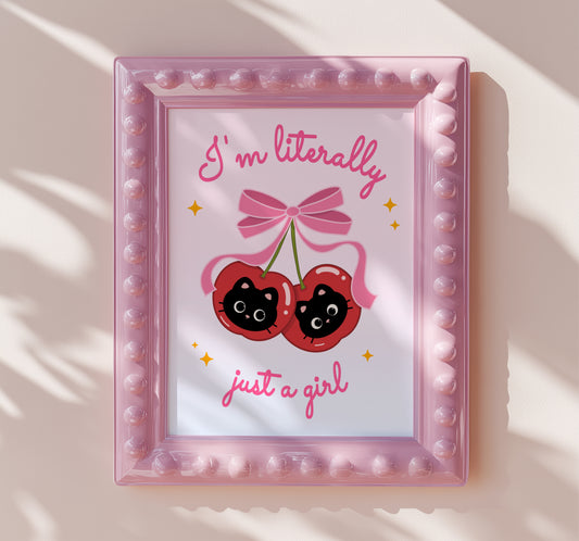 Pair of shiny red cherries with black kitten faces and a big pink bow, with the phrase “I’m literally just a girl.”