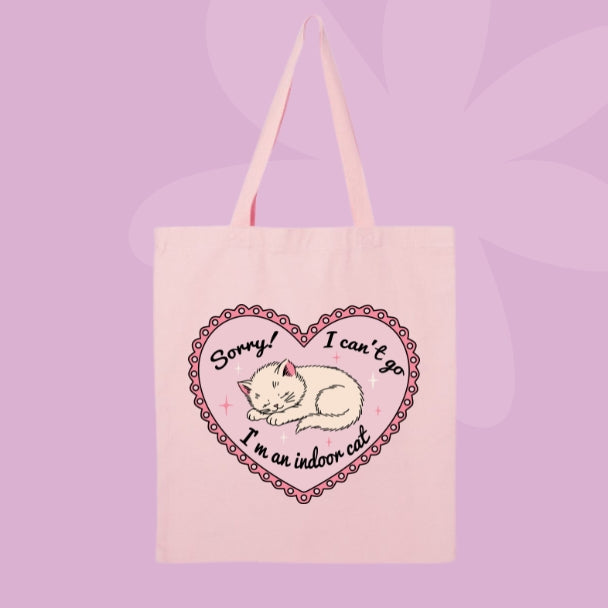 Pink canvas tote bag featuring a sleepy kitten inside a pink heart with text that says Sorry! I can’t go, I’m an indoor cat.