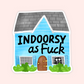 A die-cut sticker featuring a cartoon house with the text 'INDOORSY as Fuck' in black lettering. The house has light blue siding, a gray shingled roof, a brown door, green bushes, and a black cat peeking out of one window.