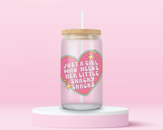 Pink heart glass can tumbler with the phrase “Just a Girl Who Needs Her Little Snacky Snacks” in sparkly retro lettering.
