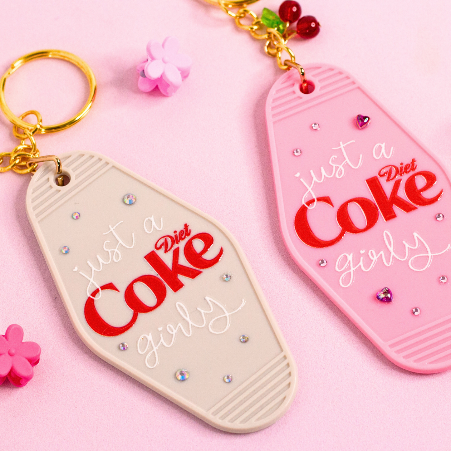 close up of pink and grey motel keychains with red Diet Coke girly text, rhinestone details and gold key rings