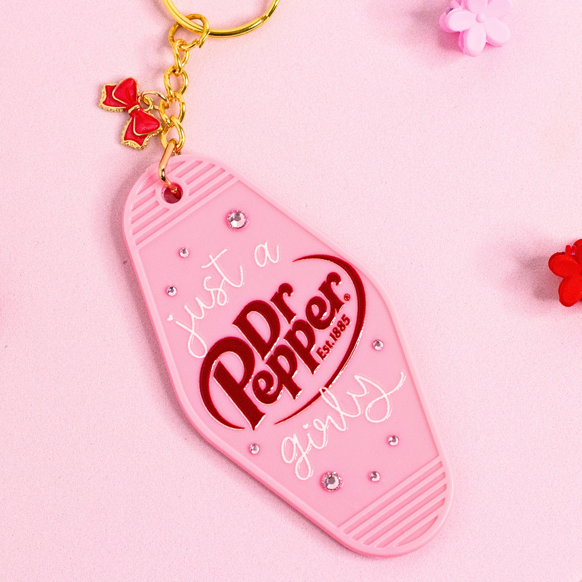 pink motel style keychain with “just a Dr Pepper girly” text, rhinestones and bow charm on pink background