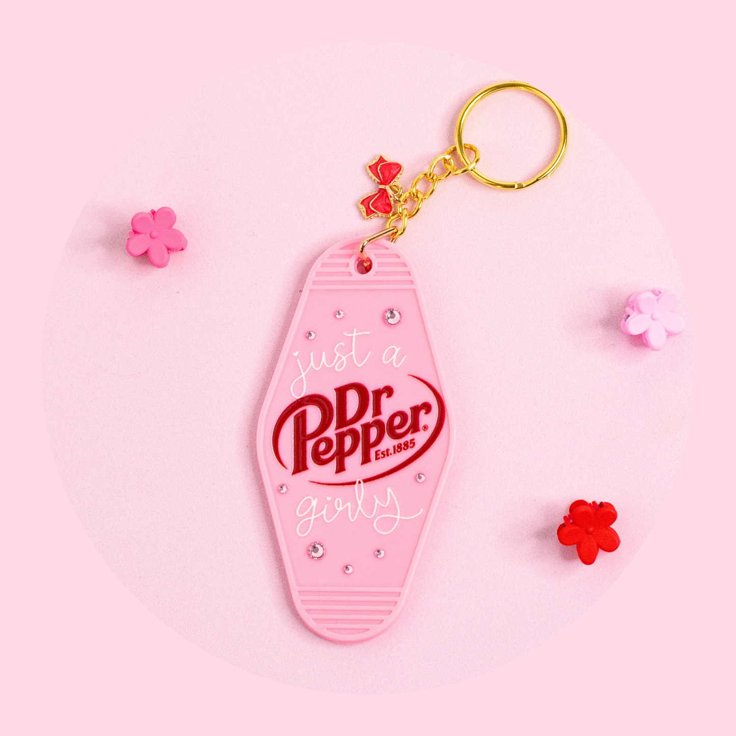 pink retro keychain with Dr Pepper girly design, glossy lettering and sparkly details styled on soft pink surface with small flowers