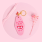 pink retro keychain with cherries and bow design, girly text and sparkly details styled on soft pink surface with flowers