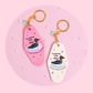 pink and white retro motel keychains with loon design and text, sparkly details and gold hardware styled on soft pink surface