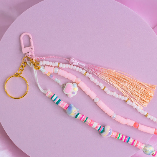 Pink and pastel purse charm with rainbow beads, pearl details, a cat paw charm, and shiny tassel on a pink clasp.