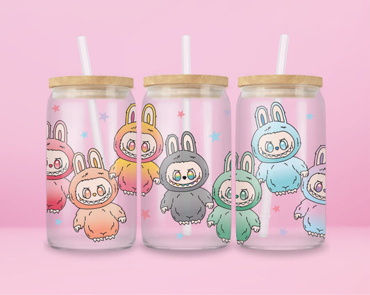 Glass tumbler with colorful Labubu characters in bunny suits (pink, orange, gray, green, blue) on a pastel pink background with stars.