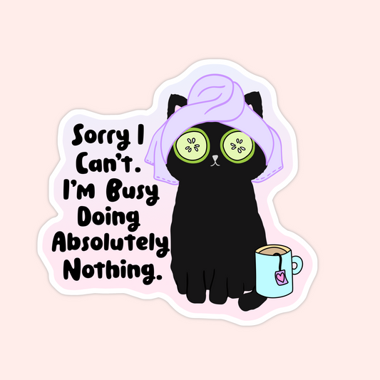 Black cat with cucumber slices on eyes, towel on head, and tea mug beside it with text that says “Sorry I can’t, I’m busy doing absolutely nothing.”