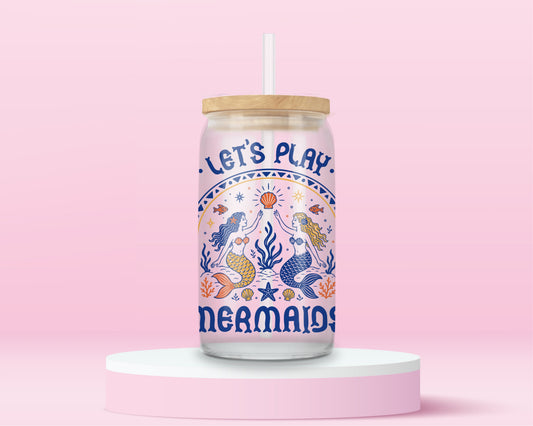 Glass can tumbler with bamboo lid and glass straw featuring retro-inspired mermaids, seashells, starfish, coral, fish, and the words Let’s Play Mermaids on a pink background.