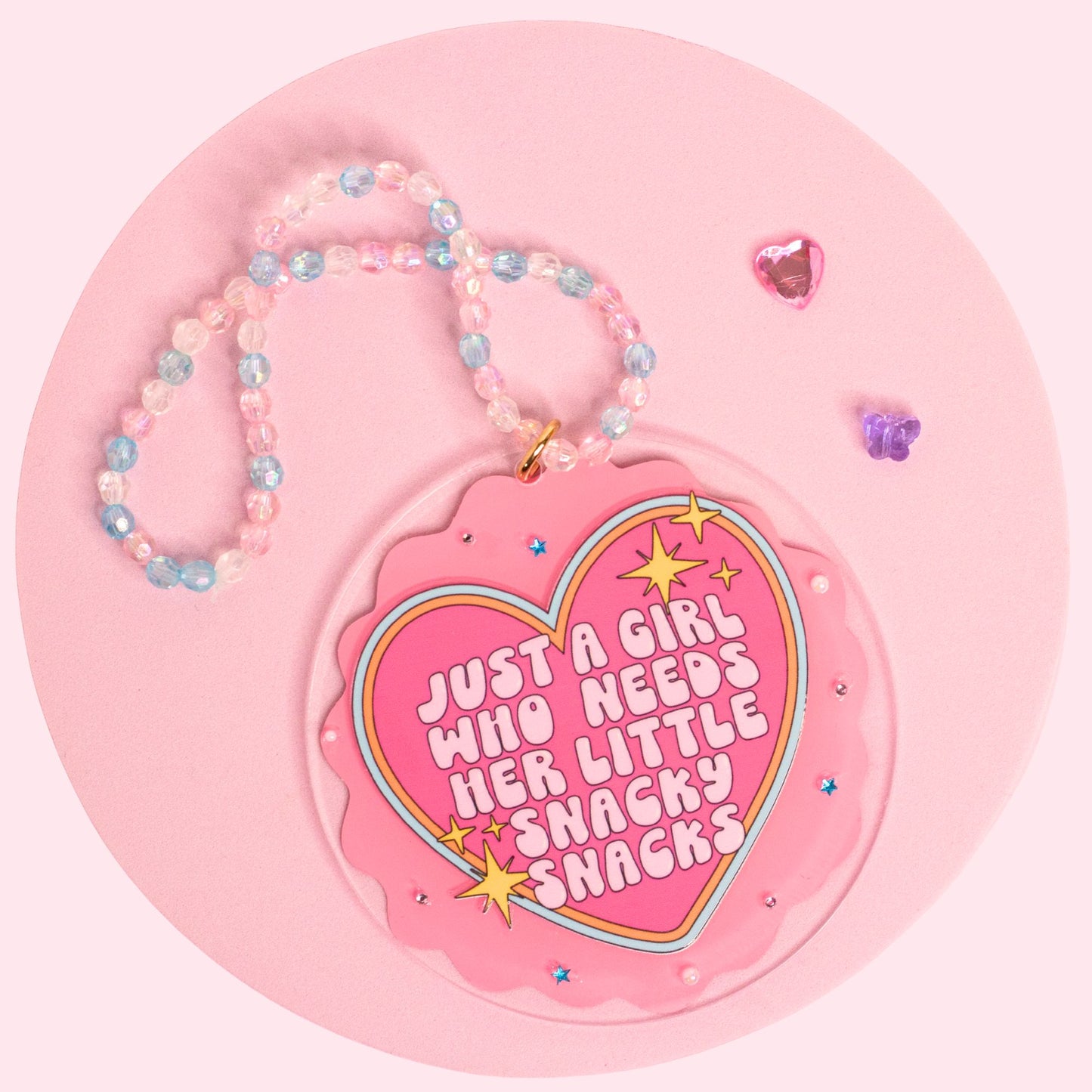 Little Snacky Snacks car charm with a pink heart design, retro lettering, sparkly details, and a pastel handmade beaded hanger.