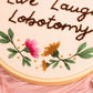 Detailed close-up of embroidered pink and yellow flowers with green leaves and gold bead embellishments