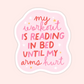 Pink sticker with mixed script and bold lettering that reads “My workout is reading in bed until my arms hurt” with small star accents.