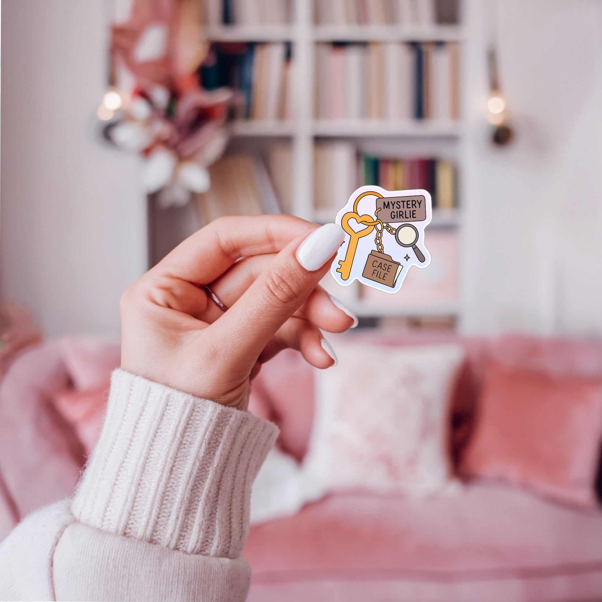 Pastel sticker showing a heart key with a “Mystery Girlie” tag, a magnifying glass charm, and a case file charm for cozy mystery readers.