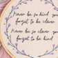 Close up detail of embroidered quote and purple floral border in wooden embroidery hoop wall art