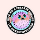 Round sticker featuring a pastel pufferfish with teary eyes and the text "Give me a freakin minute I’m overstimulated."