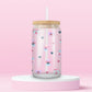 Glass cup with pastel pansies, navy blue hearts, and star sparkles on a soft pink background.