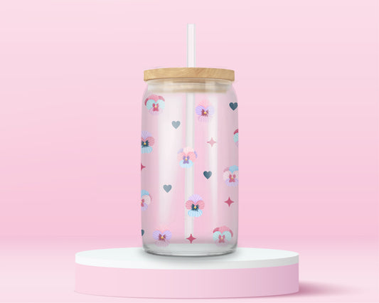 Glass cup with pastel pansies, navy blue hearts, and star sparkles on a soft pink background.