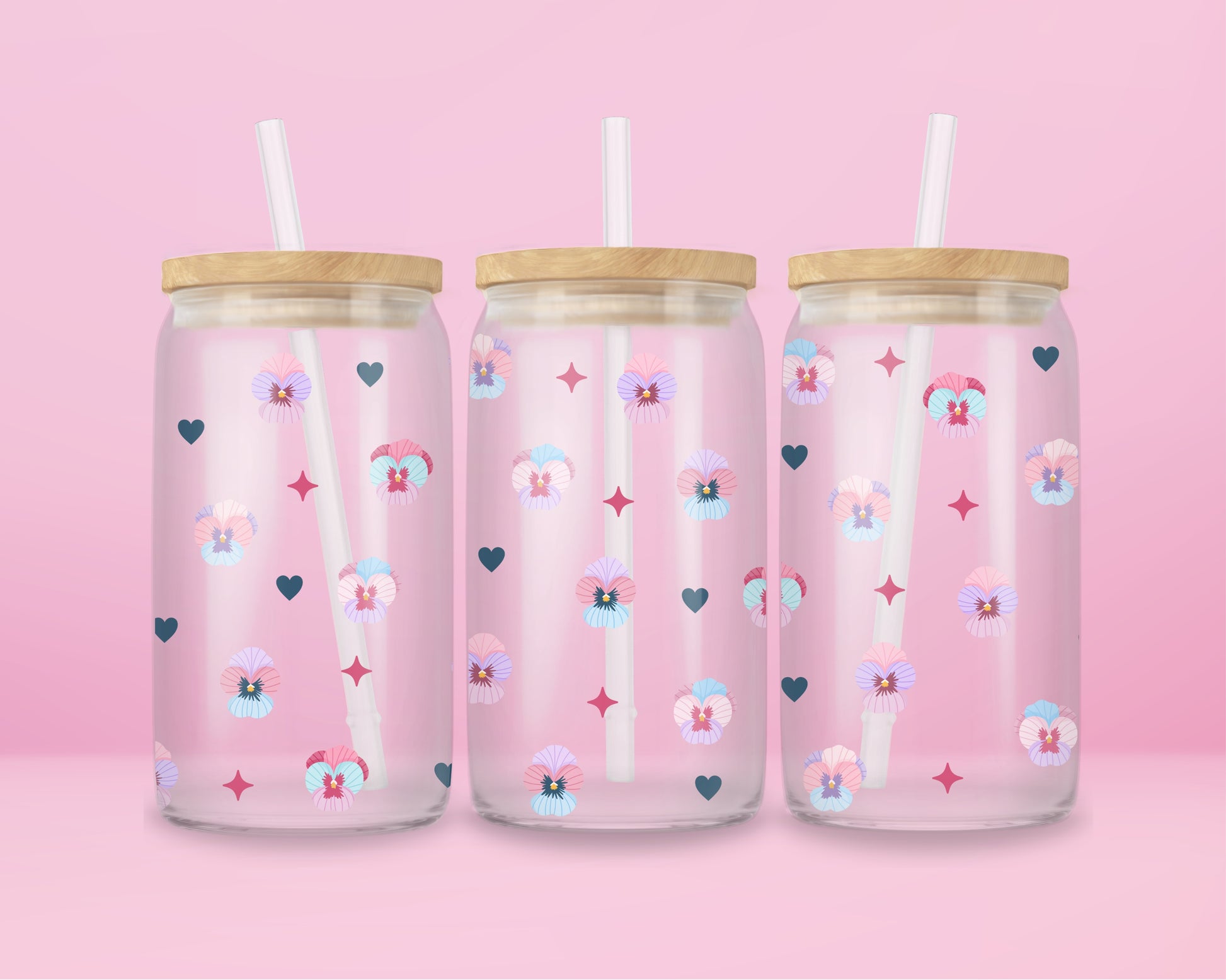 Glass cup with pastel pansies, navy blue hearts, and star sparkles on a soft pink background.