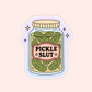 A pink-labeled glass jar full of pickles with bold text “Pickle Slut” in the center.
