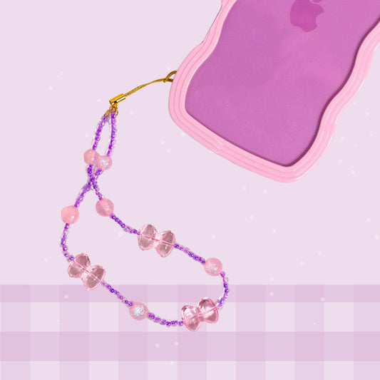 Pink bow beaded phone wristlet with purple beads, pink bow charms, glittery pink accent beads, and a gold phone strap attachment.