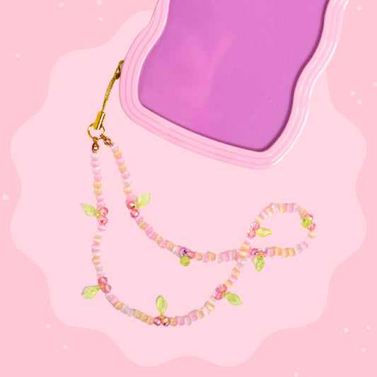Pink cherry beaded phone wristlet with pastel beads, pink cherry charms, green leaf details, sparkly accents, and a gold phone strap attachment.
