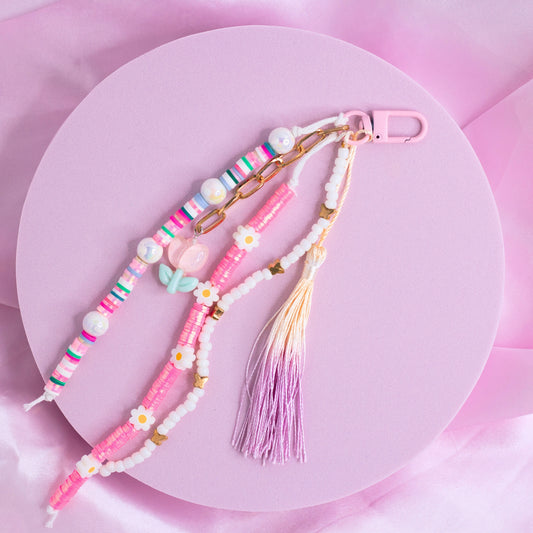 Pink and white purse charm with daisy beads, pastel accents, heart beads, and a purple tassel on a pink clasp.