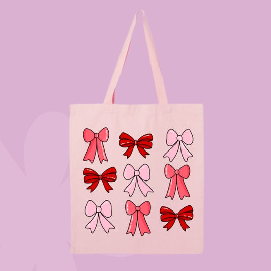 Pink tote bag with nine red and pink bow illustrations in a cute repeating grid pattern.