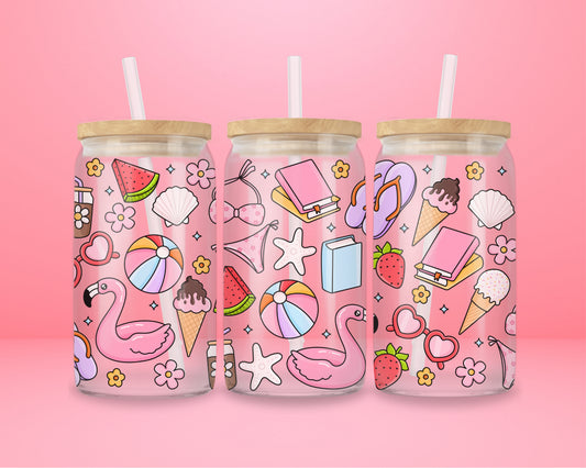 Glass can tumbler with bamboo lid and glass straw featuring a pink flamingo float, beach ball, watermelon, sunglasses, iced coffee, flowers, seashells, and ice cream on a pink background.