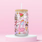 Glass can tumbler with bamboo lid and glass straw featuring a pink flamingo float, beach ball, watermelon, sunglasses, iced coffee, flowers, seashells, and ice cream on a pink background.