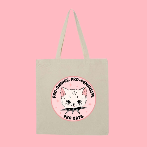 Beige tote bag with a circular design featuring a white cat head and text that says “Pro Choice, Pro Feminism, Pro Cats.”