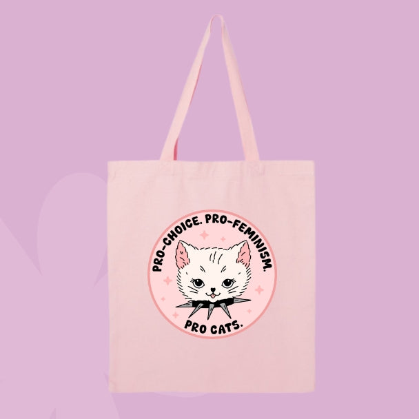 Pink tote bag with a circular design featuring a white cat head and text that says “Pro Choice, Pro Feminism, Pro Cats.”
