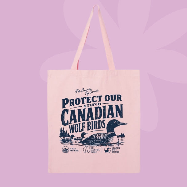 Pink canvas tote bag featuring navy vintage-style text that says Protect Our Stupid Canadian Wolf Birds with a loon and lake illustration.