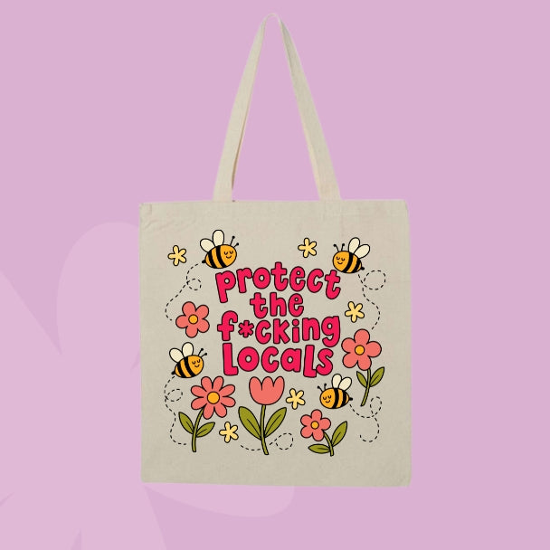 Beige canvas tote bag featuring flowers, bees, and bold pink text that says Protect The F*cking Locals.