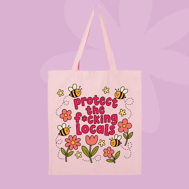 Pink canvas tote bag featuring flowers, bees, and bold pink text that says Protect The F*cking Locals.