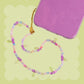 Purple cherry beaded phone wristlet with pastel rainbow beads, purple cherry charms, green leaf details, sparkly pink accents, and a gold phone strap attachment.
