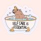 Cute vinyl sticker featuring a capybara relaxing in a bubble bath with a rubber duck and the phrase “Self Care Is Essential.”