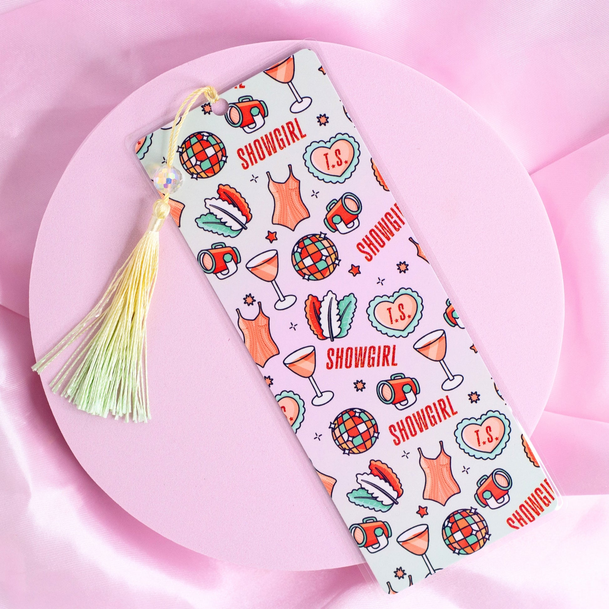 White bookmark with repeating disco balls, cocktails, corsets, and “Showgirl” text, finished with a pastel tassel.